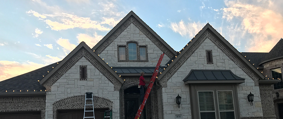 Professional from Integra Pest & Lawn installing christmas lights for a home in Arlington, TX.